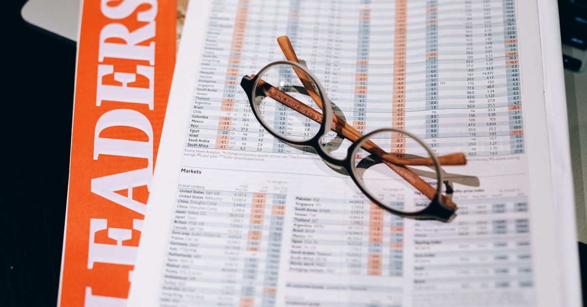A pair of eyeglasses resting on a financial document and magazine with bold headline "LEADERS" in focus.